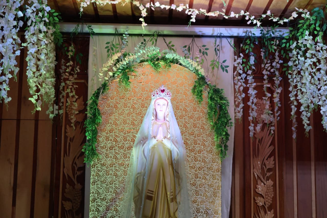 The statue of Our Lady crowned at her shrine in the parish, dressed with flowers for her feast