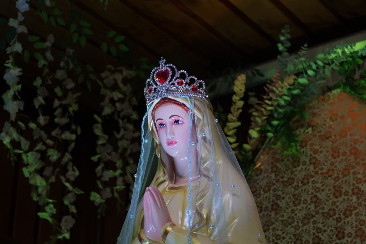 The crowned statue lit warmly against the dark wood of the sanctuary