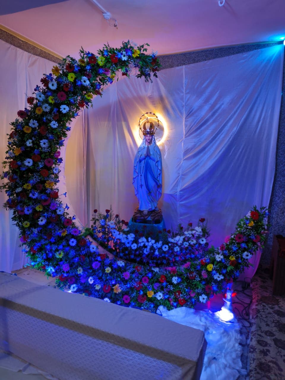 The statue of Our Lady of Lourdes set within a floral crescent